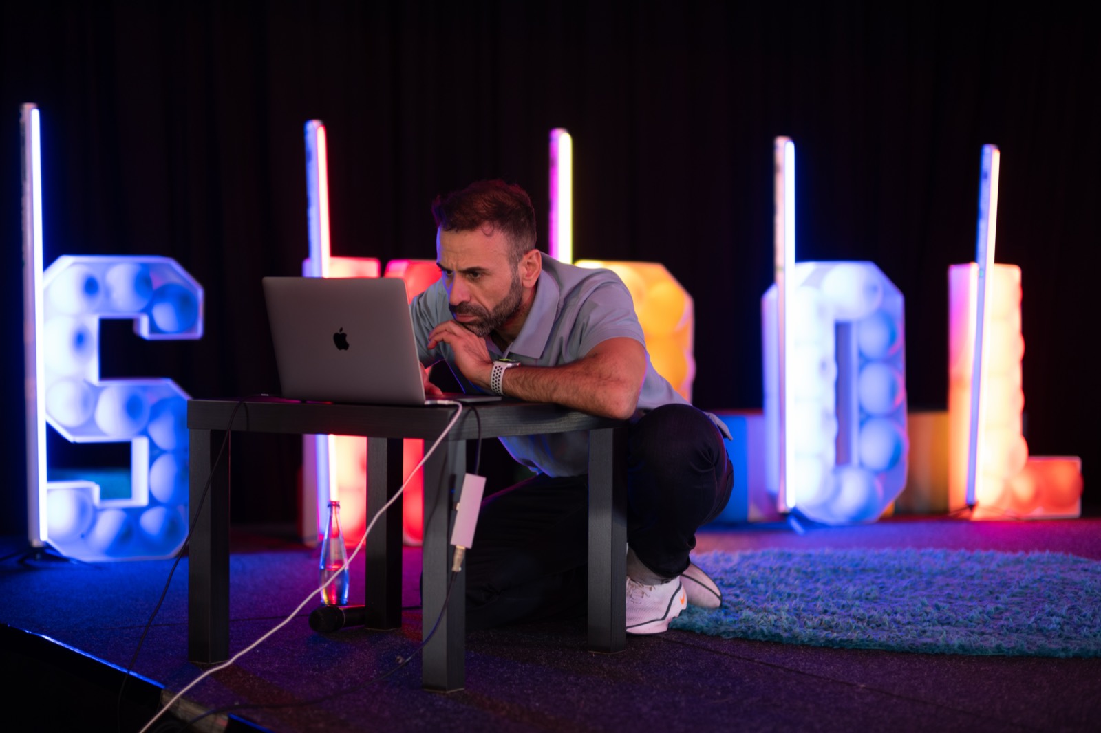 Fadi arbeitet backstage am Laptop vor der Eventbühne